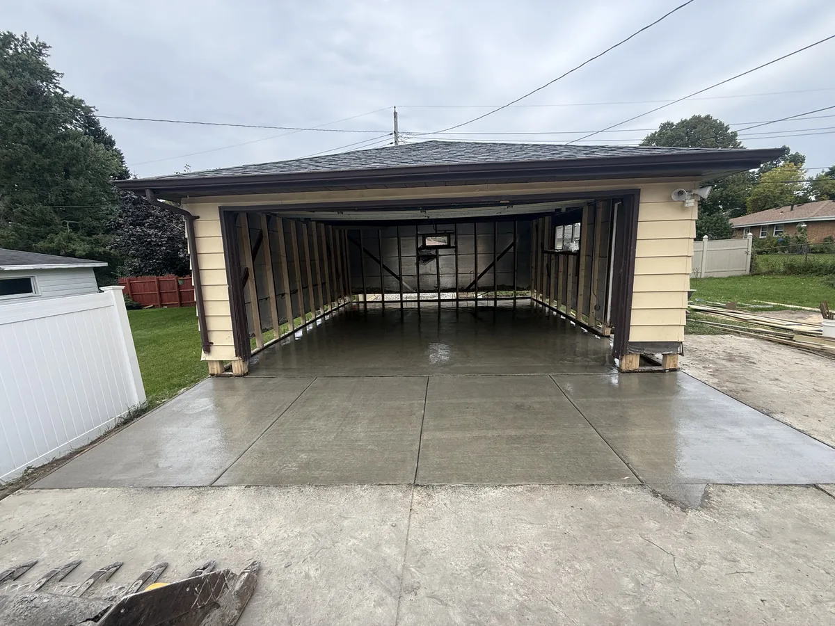 Fresh concrete driveway leading to a detached garage