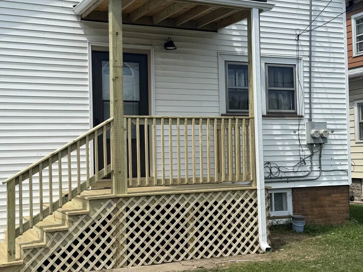 Covered wood porch with stairs, railings and lattice