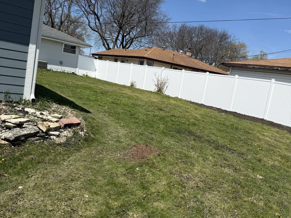 White vinyl privacy fence along a backyard lot line