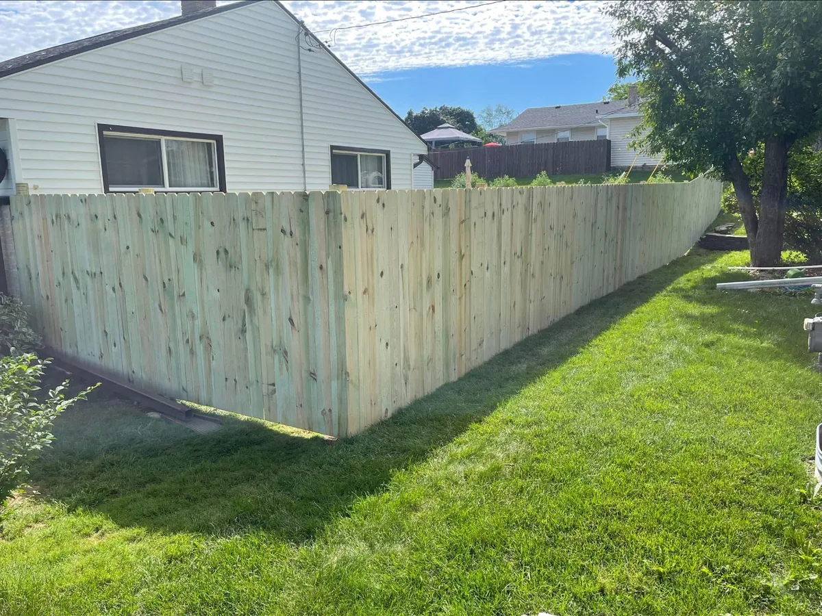 Pressure-treated wood privacy fence along a backyard